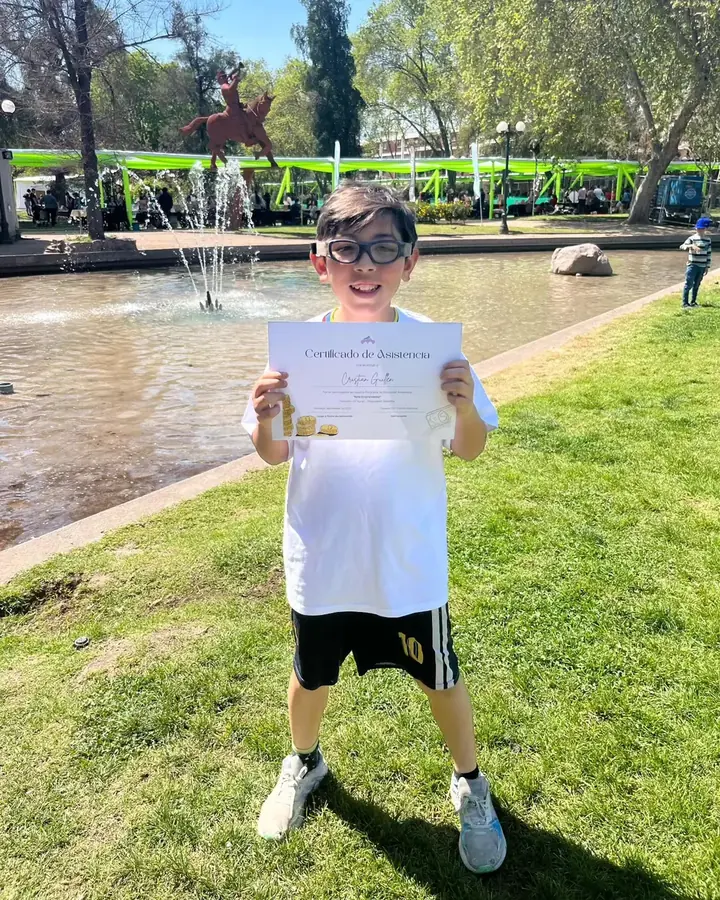 Niño mostrando con alegría su certificado de participación